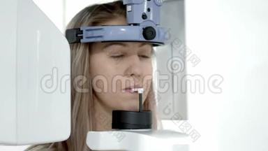 一台牙科X光扫描仪，对年轻金发女子的下颚进行全景摄影。
